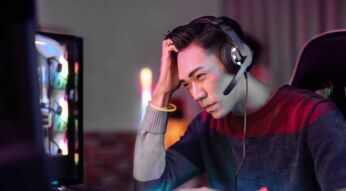 Ein Gamer sitzt am Schreibtisch und fasst sich an den Kopf