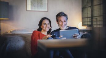 Paar schaut TV auf Fernseher und Tablet