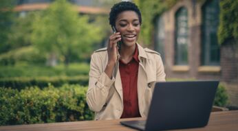 Frau am Handy vor Laptop