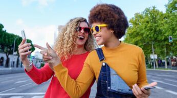 Zwei fröhliche junge Frauen mit Smartphone