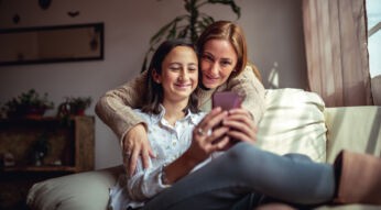 Auf dem Bild in dem Artikel zu den Vodafone Familientarifen ist eine Frau und eine junge Frau auf einem Sofa mit einem Handy zu sehen.