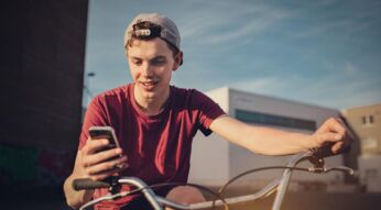 Jugendlicher auf Fahrrad mit Smartphone