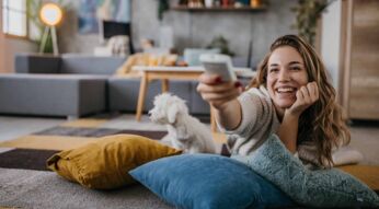 Eine Frau liegt auf dem Boden vor dem Fernseher