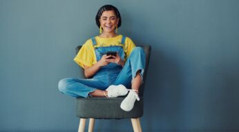 Junge Frau auf Stuhl mit Smartphone