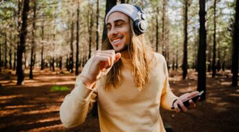 Junger Mann hört via Tidal Musik im Wald