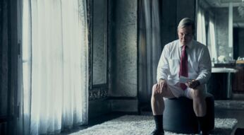 Ein Mann sitzt allein in einem großen Raum.