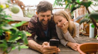 Vater und Tochter mit Smartphone auf dem Balkon