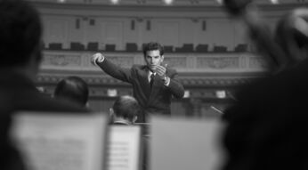 Bradley Cooper als Leonard Bernstein beim Dirigieren eines Orchesters im Film Maestro
