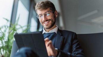 Ein Mann sitzt auf der Couch und hat sein Tablet in der Hand