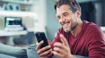 Lächelnder Mann bei einem Videoanruf mit seinem Smartphone in der Hand