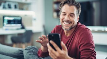 Mann schaut lächelnd auf sein iPhoe