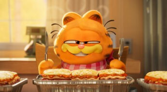 Garfield sitzt mit Messer und Gabel an einem Tisch. Vor ihm eine große Portion Lasagne.
