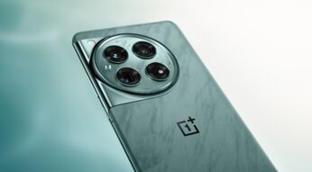 Die Rückseite des Smartphones OnePlus 12 mit rundem Kameramodul in Grün vor einem weiß-grünen Hintergrund