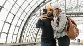Ein junges Paar, das ihr Smartphone für ein Selfie nutzt.