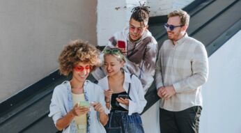 Vier junge Leute amüsieren sich mit ihren Smartphones.