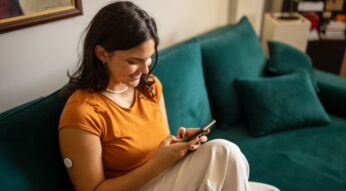 Frau schaut lächelnd auf ihr Android-Handy.