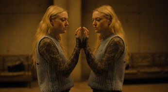 Die Hauptfigur Mina steht an der Glasscheibe des Bunkers