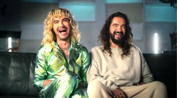 Bill und Tom Kaulitz sitzen nebeneinander auf dem Sofa und lachen.