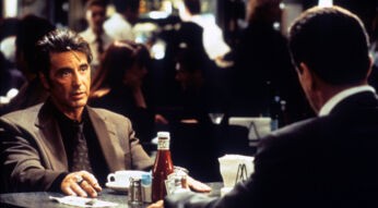 Das Bild zum "Heat 2"-Film-Artikel zeigt eine Szene aus dem Film Heat von 1995. Al Pacino sitzt als Polizist Vincent Hanna in Anzug und Krawatte an einem Tisch und schaut seinem gegenübersitzenden Gesprächspartner ernst in die Augen. Er hat beide Hände auf den Tisch gelegt und vor ihm steht eine Kaffeetasse. In der Mitte des Tischs steht eine Ketchup-Flasche sowie Pfeffer- und Salzstreuer und ein Serviettenhalter. Auch Hannas Gegenüber trägt scheinbar einen Anzug. Der Mann ist allerdings nur von hinten zu sehen. Im Hintergrund (hinter Vincent Hanna) sieht man verschwommen weitere Menschen, die in dem Restaurant sitzen oder herumlaufen.