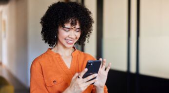 Frau lächelt und tippt auf ihr iPhone