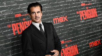 Auf dem Bild ist Colin Farrell zu sehen, der die Hauptrolle als Oswald Cobblepot, auch bekannt als der Pinguin, in der Serie "Der Pinguin" spielt. Farrell trägt einen eleganten, dunklen Nadelstreifenanzug und steht vor einer schwarzen Backsteinwand mit den roten Logos von HBO und der Serie "The Penguin". Das Bild ist auf der Premiere entstanden. Seine Haltung wirkt selbstbewusst und leicht nachdenklich.