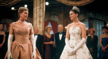 Auf dem Bild zu "Plötzlich Prinzessin 3" sind Anne Hathaway als Mia Thermopolis und Julie Andrews als Königin Clarisse Renaldi in einer eleganten Ballszene zu sehen. Beide tragen festliche Kleider: Mia ein weißes Ballkleid mit Blumenstickerei und Tiara, während Clarisse ein roséfarbenes Kleid mit langen Handschuhen und Diamantschmuck trägt. Sie tauschen ein stolzes, warmes Lächeln aus, umgeben von elegant gekleideten Gästen im Hintergrund.