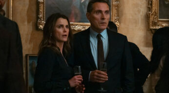 Ehepaar Wyler steht auf einem Empfang und schaut überrascht.