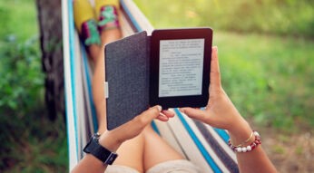 Ein Person liegt in der Hängematte und liest aus einem E-Reader.