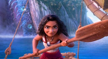 Auf dem Bild in dem Artikel über den möglichen Film Vaiana 3 ist Vaiana zu sehen, wie sie entschlossen ein hölzernes Paddel hält. Sie trägt ein traditionelles, rot-weißes Outfit mit einer Muschelkette. Im Hintergrund ist ein riesiges, schuppenartiges Wesen mit leuchtenden blauen Augen und eine Wasserlandschaft vor steilen Felswänden zu erkennen.