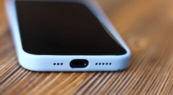 Ein iPhone 15 mit USB-C-Anschluss liegt auf einem Holztisch