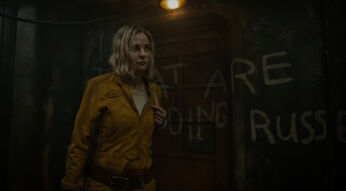 Auf dem Bild im Silo Staffel 3 Artikel ist Rebecca Ferguson als Juliette zu sehen. Sie trägt einen gelben Overall und steht in einem düsteren, heruntergekommenen Raum mit Graffiti an der Wand. Ihr ernster Blick und die düstere Beleuchtung unterstreichen die angespannte Stimmung.
