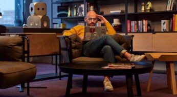 Ein Mann sitzt in der Lobby von Netflix Amsterdam und schaut Netflix auf seinem MacBook.