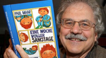 Kinderbuchautor Paul Maar hält das Buch „Eine Woche voller Samstage“ in der Hand