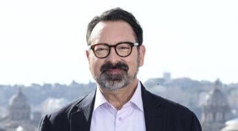 Auf dem Bild in dem Artikel zu Dawn of the Jedi ist James Mangold zu sehen. Er trägt eine dunkle Brille, hat einen gepflegten Bart und trägt ein helles Hemd mit einem dunklen Sakko. Im Hintergrund erstreckt sich eine Stadtlandschaft mit historischen Gebäuden und Kuppeln. Mangold lächelt leicht und blickt direkt in die Kamera, was eine freundliche und selbstbewusste Ausstrahlung vermittelt.