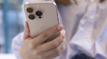 Kundin hält im Apple Store ein iPhone 16 Pro in Weiß in der Hand