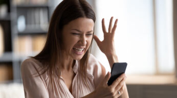 Eine Frau schaut verärgert auf ihr Smartphone.