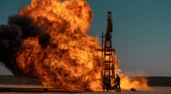 Arbeiter stehen um eine Ölbohrung herum, die Feuer gefangen hat.