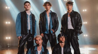 Auf dem Bild zum Film Back to the 90s stehen fünf junge Männer in Lederjacken und Jeans auf einer Bühne im Scheinwerferlicht. Julien spielt Matteo, Tim spielt Jonas, Luis spielt Chris, Jacob spielt Ben und Bene spielt Oliver. Die Szene erinnert an eine nostalgische Boyband-Ästhetik im Stil der 90er-Jahre und wirkt selbstbewusst und dynamisch.