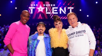 Auf dem Bild zur Show Das Supertalent 2025 ist die Jury mit Bruce Darnell, Tony Bauer, Ekaterina Leonova und Dieter Bohlen zu sehen. Vor einer leuchtenden Bühne mit dem Show-Logo posieren sie lächelnd für die Kamera. Bruce Darnell trägt ein auffälliges pinkes Outfit, Tony Bauer eine blaue Jacke, Ekaterina Leonova ein gelbes Tüll-Oberteil und Dieter Bohlen einen weißen Hoodie mit "Camp David"-Aufdruck.