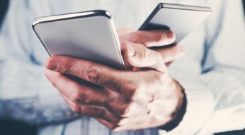 Ein Mann hält in jeder Hand ein Smartphone.