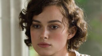Auf diesem Bild aus dem Film Abbitte ist Keira Knightley in der Rolle der Cecilia Tallis zu sehen. Sie blickt nachdenklich aus dem Fenster, ihr Gesicht wirkt ruhig, aber innerlich bewegt. Ihr braunes, leicht gelocktes Haar ist kurz geschnitten, und die Szene vermittelt eine melancholische, ernste Stimmung. Ideal für eine Übersicht zu Filme mit Keira Knightley.