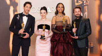Auf dem Bild von den Oscars 2025 stehen vier Gewinner:innen mit ihren goldenen Oscar-Statuetten in festlicher Abendgarderobe vor einem stilvollen Hintergrund mit dem Schriftzug "OSCARS". Von links nach rechts: Ein Mann in schwarzem Smoking mit Fliege und funkelnder Brosche, eine Frau in einem eleganten rosa Kleid, eine Frau in einer auffälligen bordeauxfarbenen Robe mit Handschuhen und ein Mann in einem schwarzen Anzug mit Fliege. Alle lächeln stolz und posieren für die Kamera.