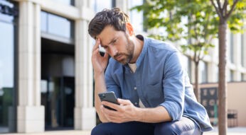 Ein Mann schaut nachdenklich auf das Display seines Smartphones.