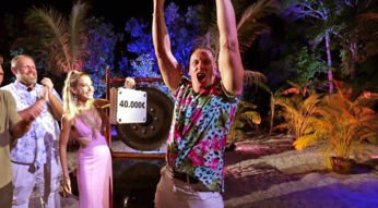 Auf dem Bild zum Thema Kampf der Realitystars-Gewinner:innen jubelt Calvin Kleinen mit erhobenen Armen über seinen Sieg. Er trägt ein auffälliges Hemd mit buntem Blumenmuster und steht im Zentrum des Geschehens. Neben ihm hält eine Frau im pinken Kleid einen Koffer mit dem Gewinnbetrag von 40.000 €. Im Hintergrund applaudieren weitere Teilnehmer:innen vor tropischer Kulisse mit Palmen und farbiger Beleuchtung.