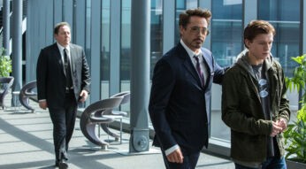 In dieser Szene aus einem der Filme von Robert Downey Jr. steht Tony Stark, gespielt von Robert Downey Jr., links im Bild und blickt ernst auf Peter Parker, dargestellt von Tom Holland. Die beiden stehen sich gegenüber in einem Moment voller Spannung und Bedeutung. Die Lichtstimmung ist dramatisch, mit urbanem Hintergrund und deutlichen Kontrasten zwischen den Figuren.