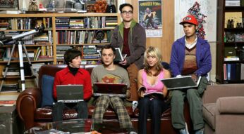Das Bild in dem Artikel zu den Serien wie The Big Bang Theory zeigt fünf Personen in einem Wohnzimmer mit Bücherregal und Teleskop. Sie sitzen eng beisammen auf einem Sofa und Stuhl, halten Laptops oder Bücher in den Händen. Die Szene wirkt freundlich und leicht nerdig, passend zum humorvollen und wissenschaftsaffinen Stil der Serie.