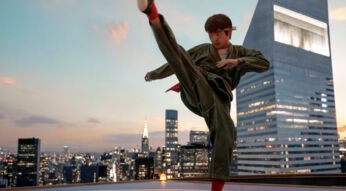 In dieser Szene aus dem Film Karate Kid: Legends ist Ben Wang als Karate Kid auf einem Hochhausdach vor der Skyline einer Großstadt zu sehen. Mit einem präzisen Tritt in der Luft und ernstem Gesichtsausdruck verkörpert er Entschlossenheit und Fokus.