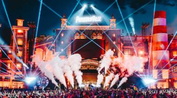 Bei diesem Bild zum Thema parookaville tickets handelt es sich um eine energiegeladene Liveszene des Parookaville-Festivals bei Nacht. Die große Hauptbühne ist festlich beleuchtet, mit leuchtenden Lasern, Rauchfontänen und einer Menschenmenge voller feiernder Besucher im Vordergrund.