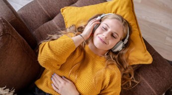 Eine Frau liegt auf dem Sofa und hört Musik.