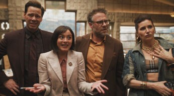 Auf dem Bild in dem Artikel zu The Studio Ende erklärt sind vier Charaktere zu sehen. Sie stehen in einem Raum. Die Figur ganz links wirkt skeptisch, daneben steht eine Frau im cremefarbenen Anzug, die lebhaft gestikuliert. Rechts daneben ein Mann mit Brille und orangefarbenem Hemd, der aufmerksam schaut. Ganz rechts steht eine Frau mit goldenen Ketten und großen Creolen, die selbstbewusst und leicht herausfordernd wirkt.